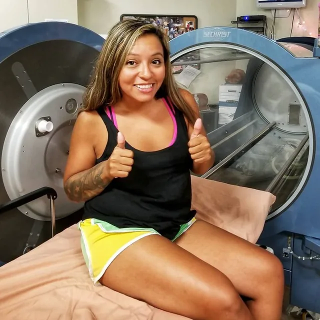 A veteran smiling beside a hyperbaric chamber