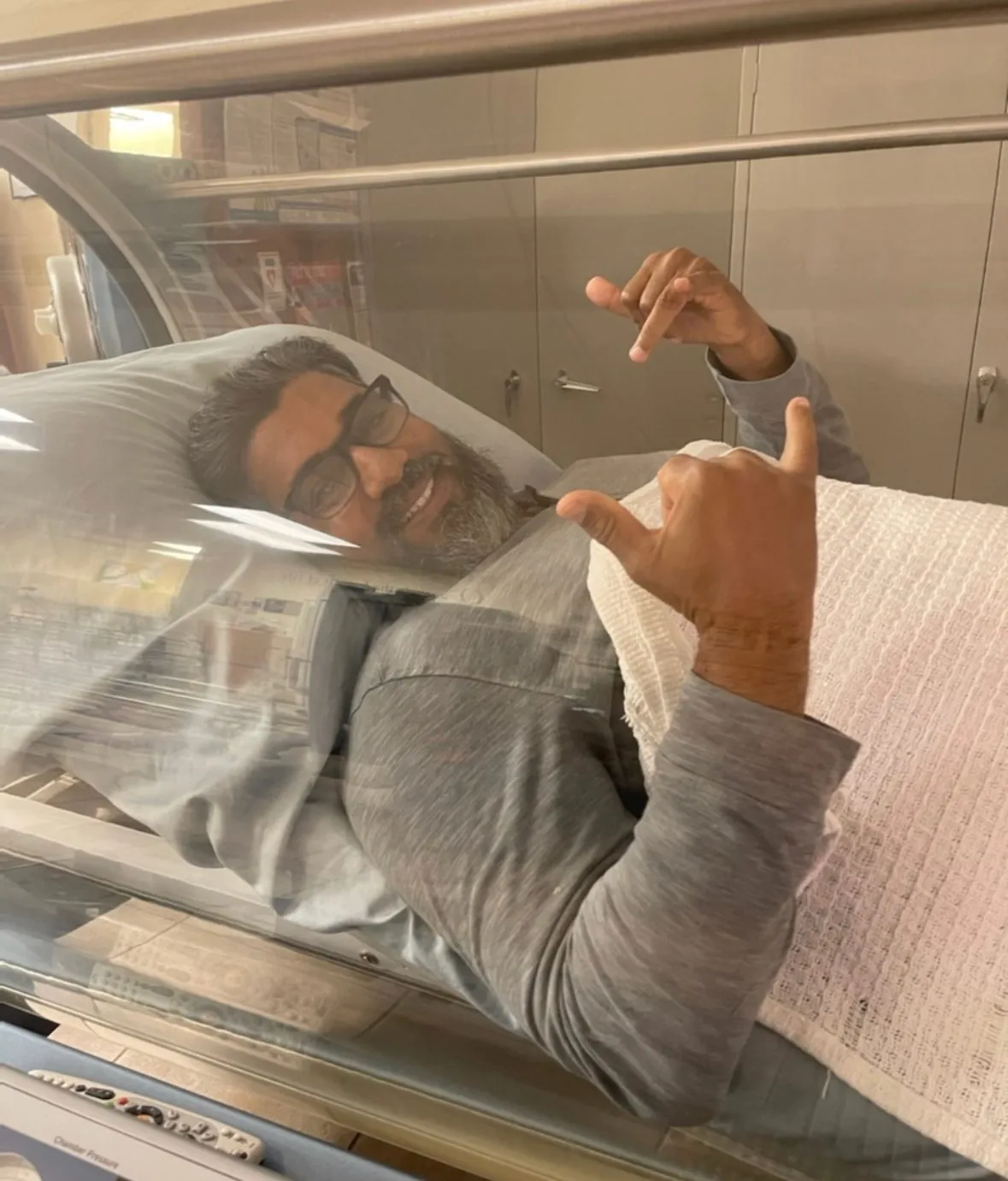 A veteran giving a shaka sign from inside a hyperbaric chamber