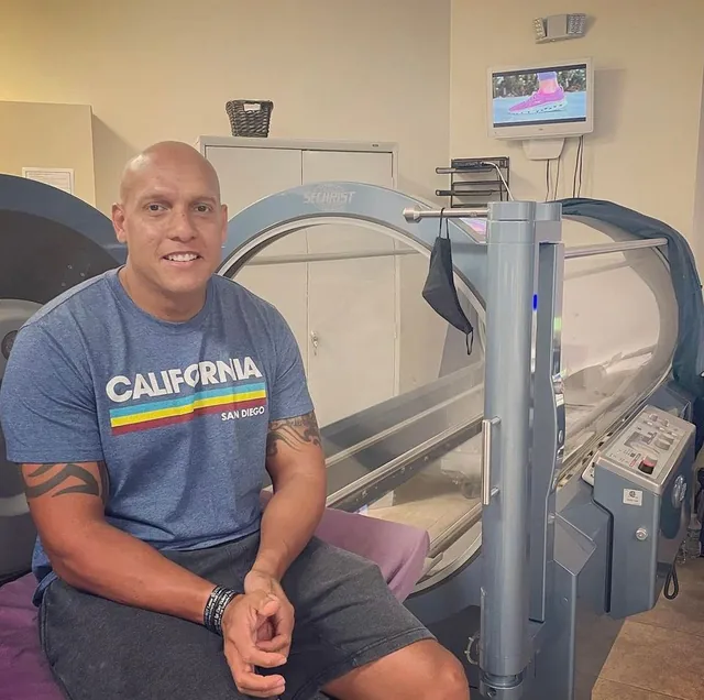 Veteran seated beside a hyperbaric chamber
