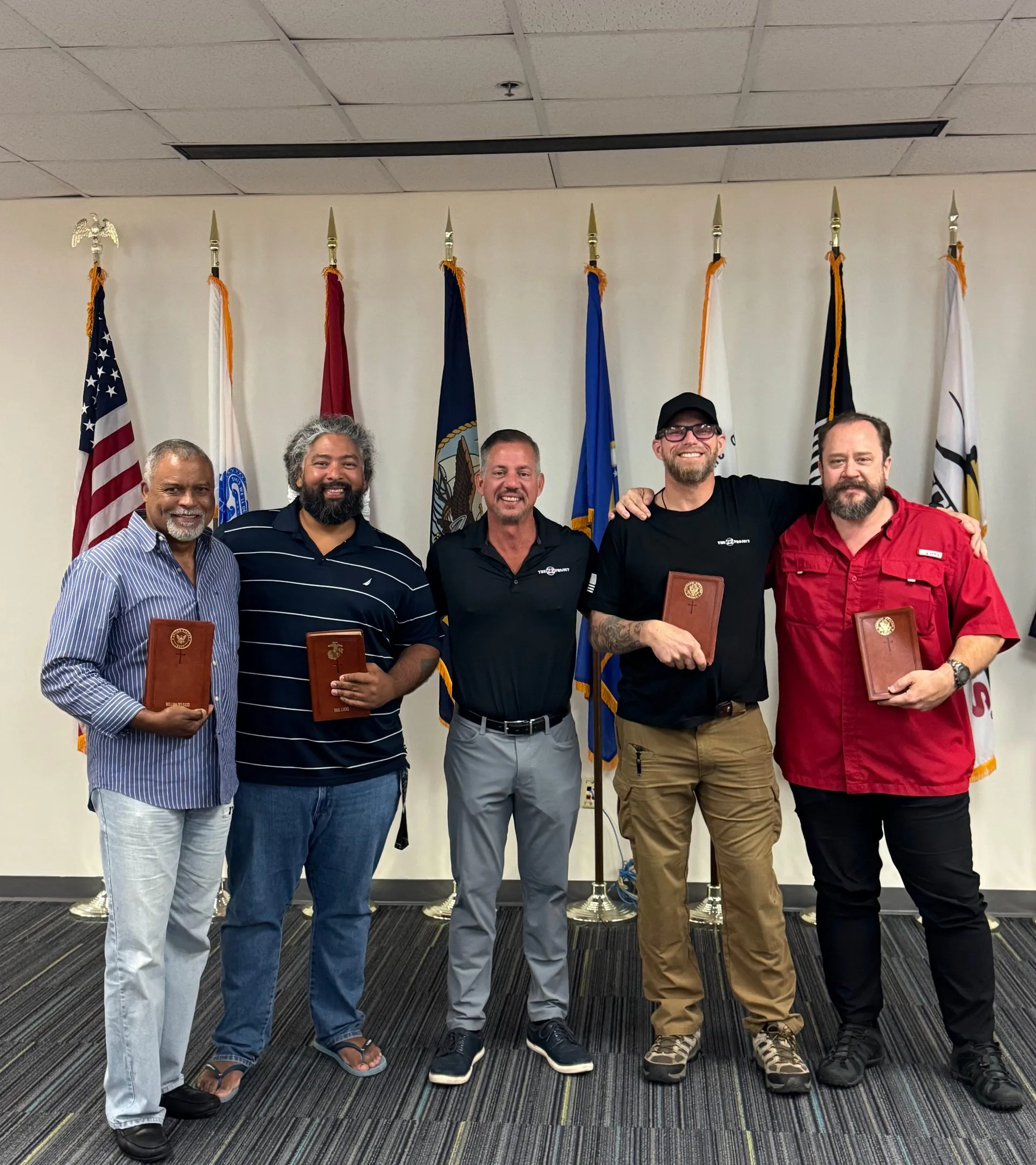 Veterans holding certificates in front of military flags